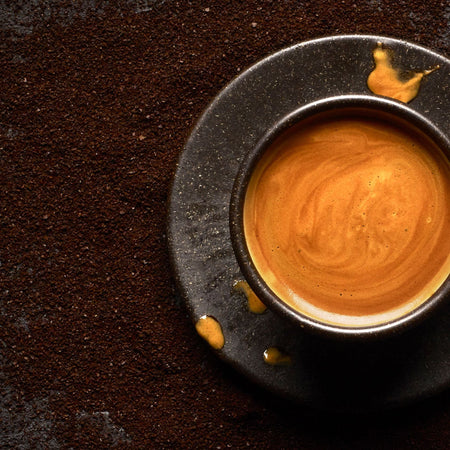Close-up of a cup of coffee on a dark textured surface