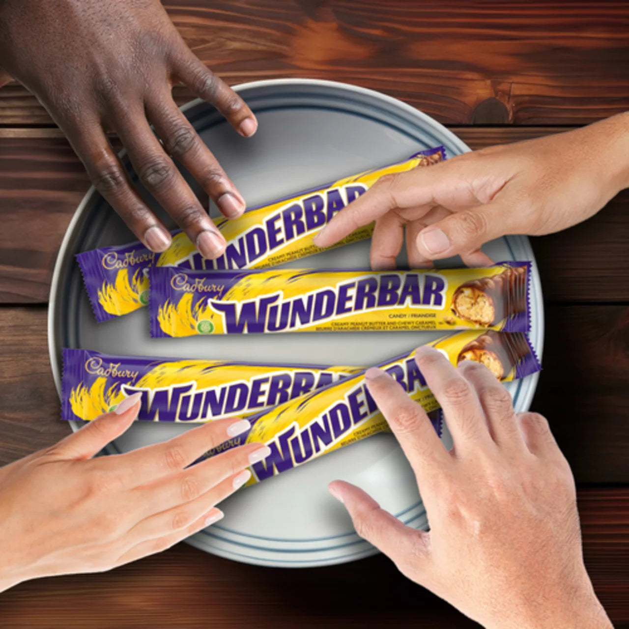 Cadbury Wunderbar chocolate bars on a tray with hands reaching for them.