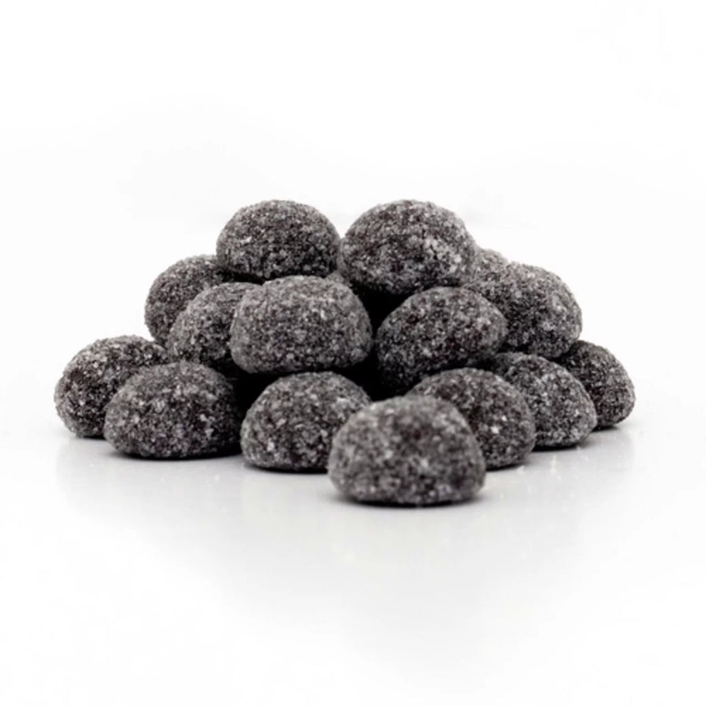 Pile of black raspberry coal gummy candies on a white background
