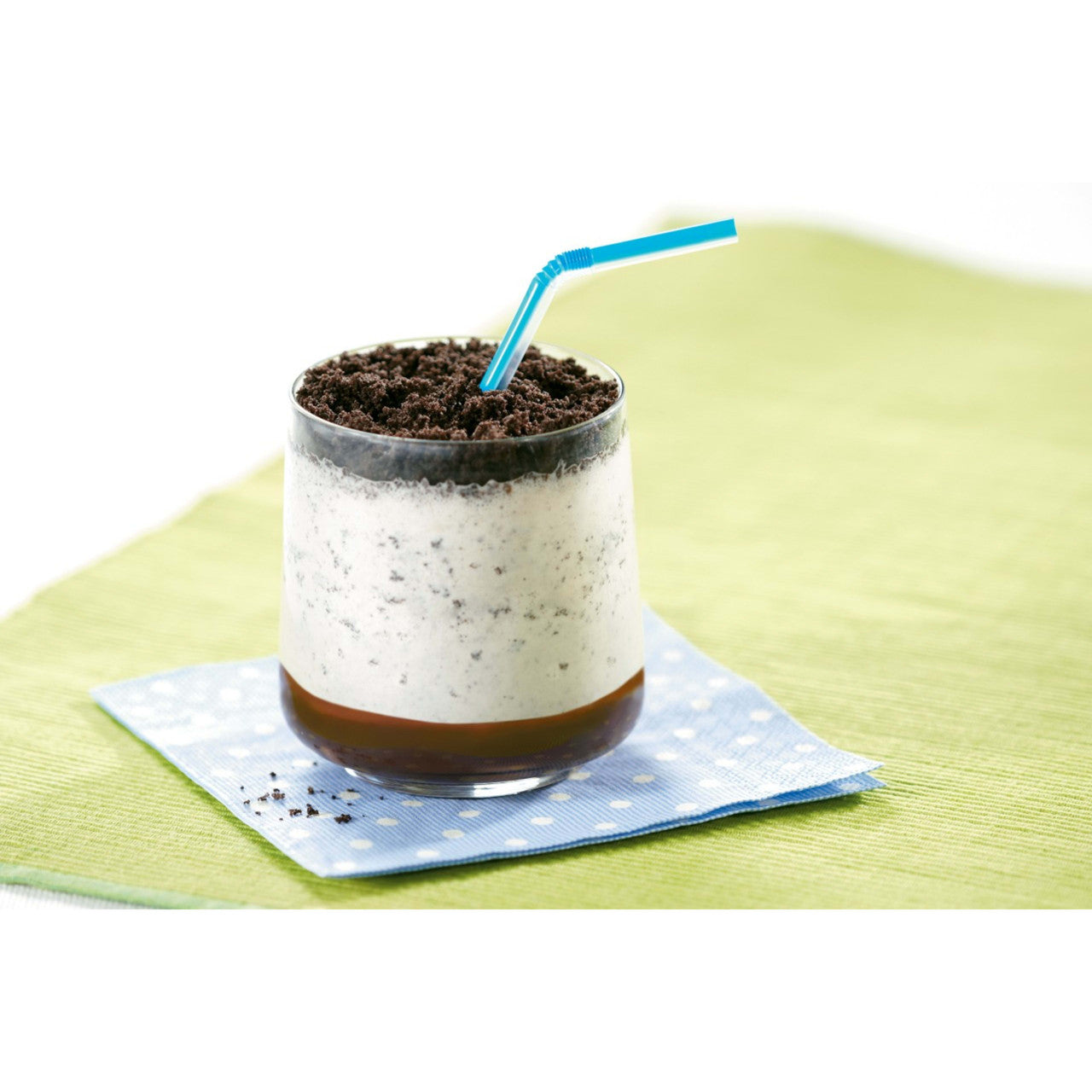 A glass of an Oreo milk shake on a light blue napkin with a green and white background