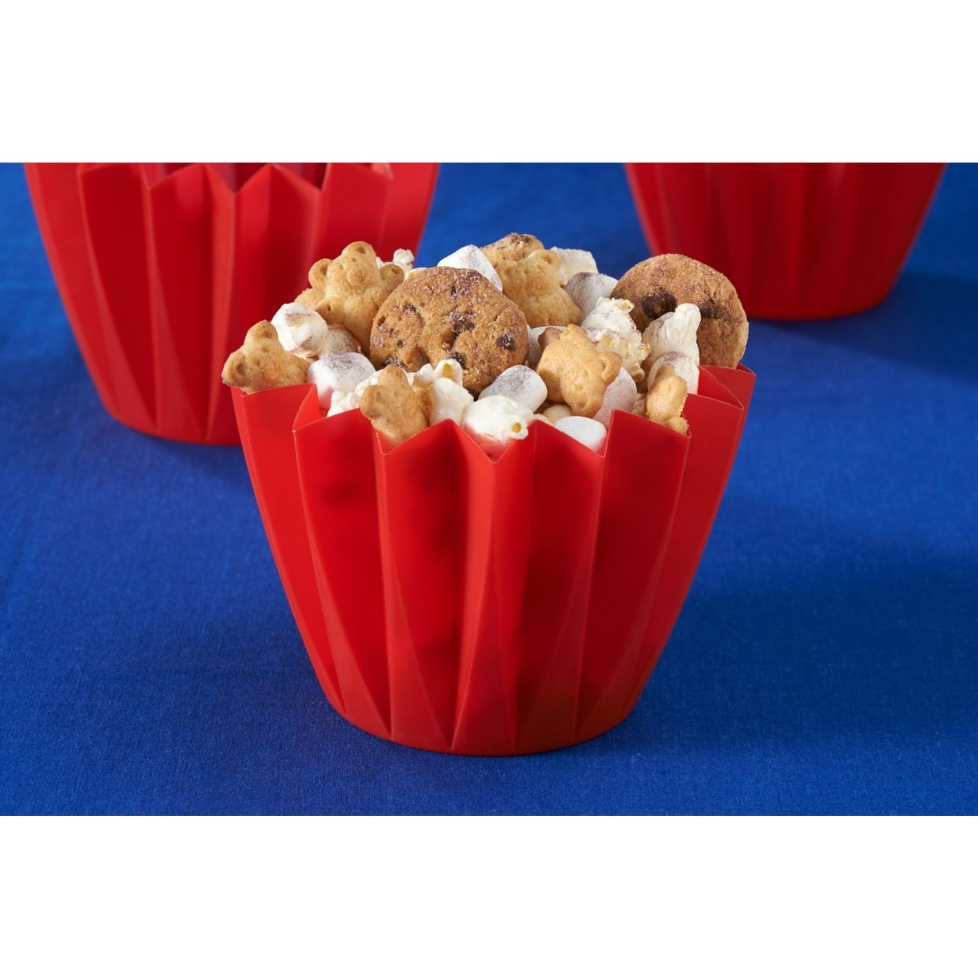 Red popcorn container filled with popcorn and cookies on a blue background