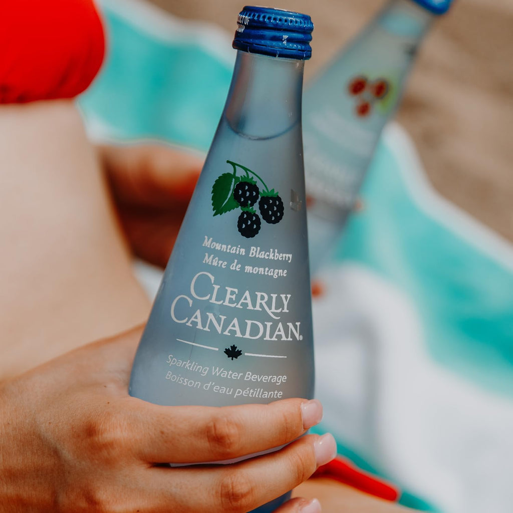 Clearly Canadian Sparkling Water Beverage, Mountain Blackberry, 325ml/11 Fl oz., Bottle, bottle on the beach.