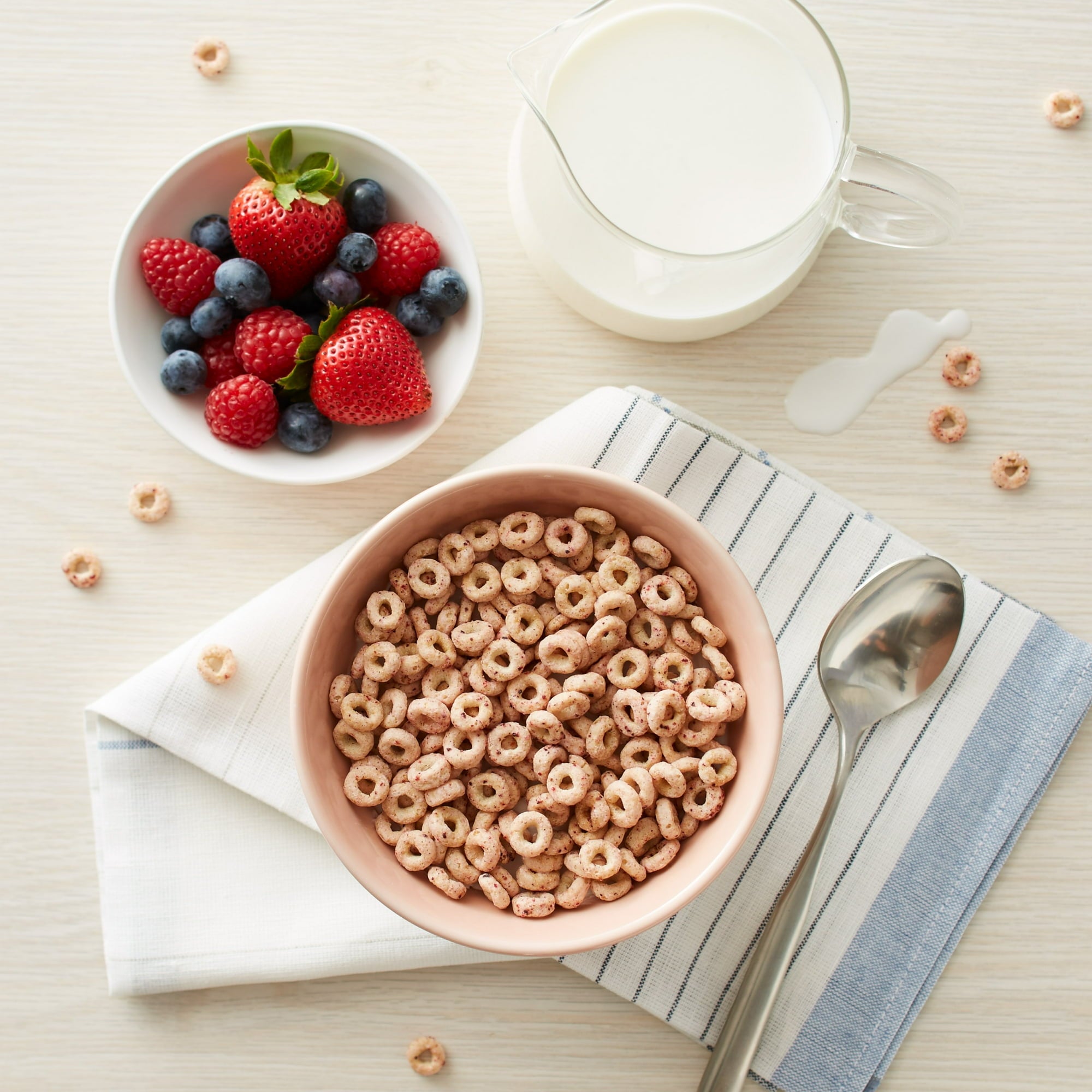 Cereal bowl with cereal, berries, and milk on a light surface