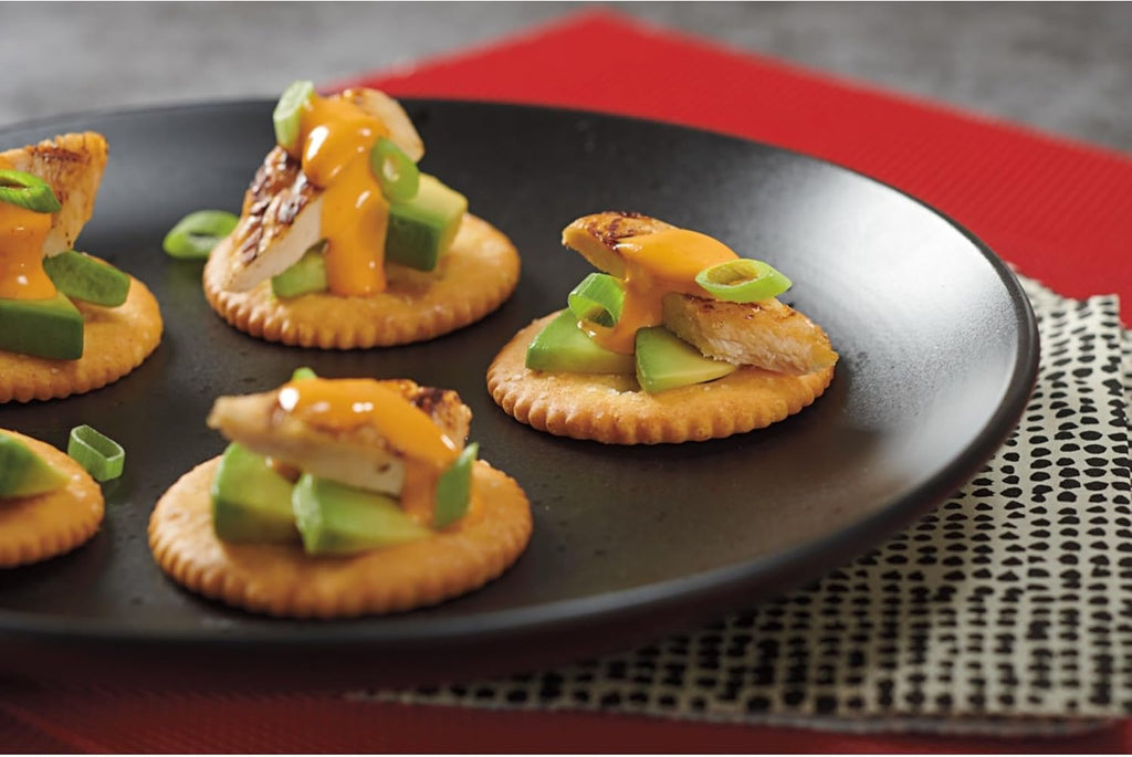 Plated appetizers with Ritz lo sodium crackers, cheese, and green onions on a black plate.
