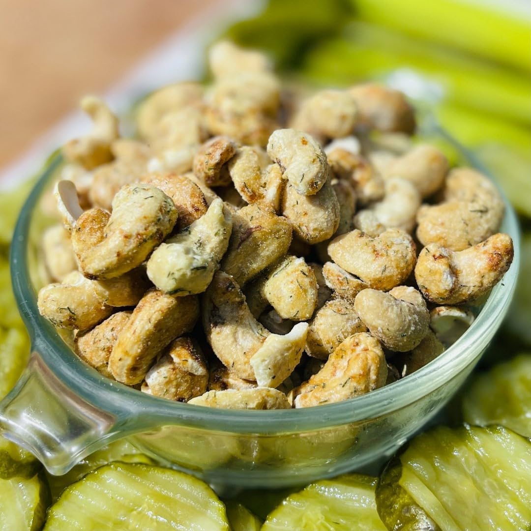 Glass bowl filled with seasoned dill pickle cashews surrounded by pickles