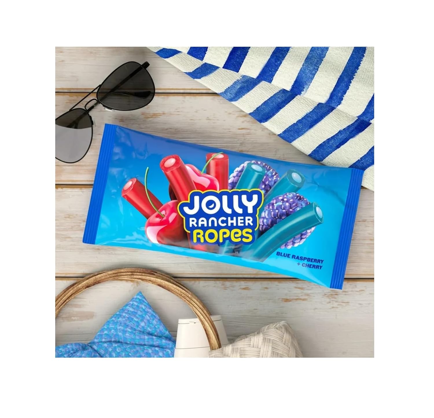 Jolly Rancher Blue Raspberry & Cherry Flavored Gummy Ropes, 283g/9.9 oz - Jolly Rancher Ropes candy package on a wooden surface with sunglasses and a towel.