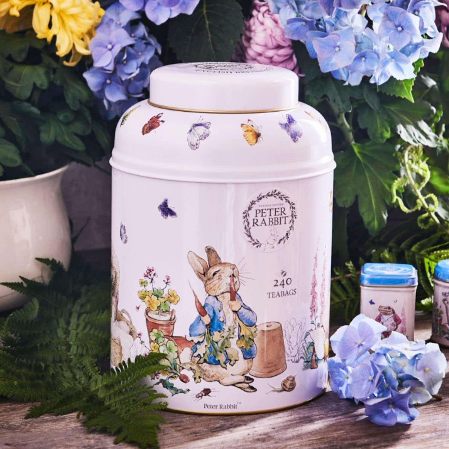 New English Teas Beatrix Potter Peter Rabbit Tea Caddy - 240 Tea Bags - Front of tea canister with Peter Rabbit design surrounded by flowers and leaves