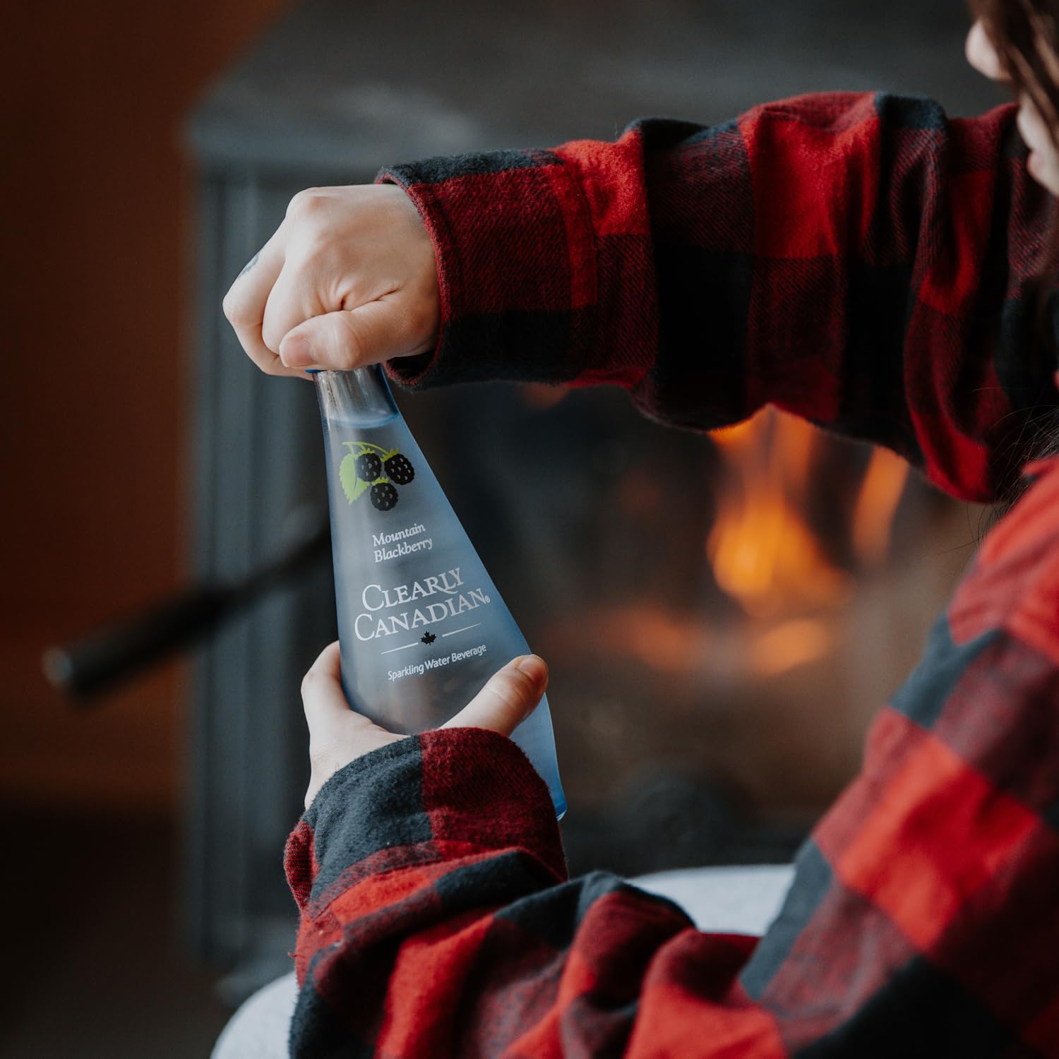 Clearly Canadian Sparkling Water Beverage, Mountain Blackberry, 325ml/11 Fl oz., Bottle, a person holding a bottle.