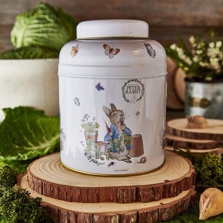 New English Teas Beatrix Potter Peter Rabbit Tea Caddy - 240 Tea Bags - Front of white metal jar with Peter Rabbit design on a wooden stand