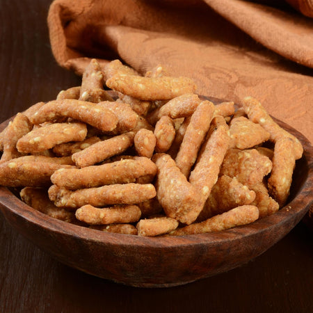 Wooden bowl filled with Yupik sesame sticks on a matching fabric background