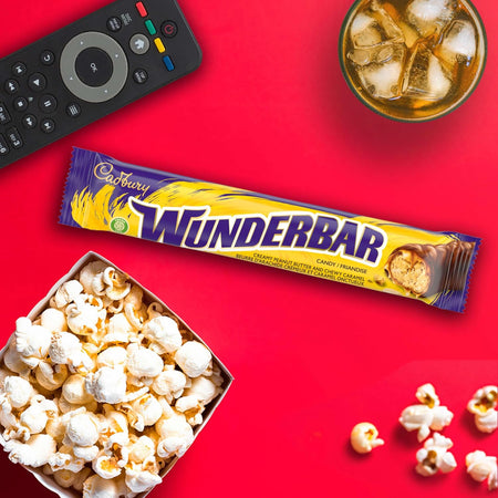 Cadbury Wunderbar candy bar with popcorn, remote control, and glass of iced tea on a red background
