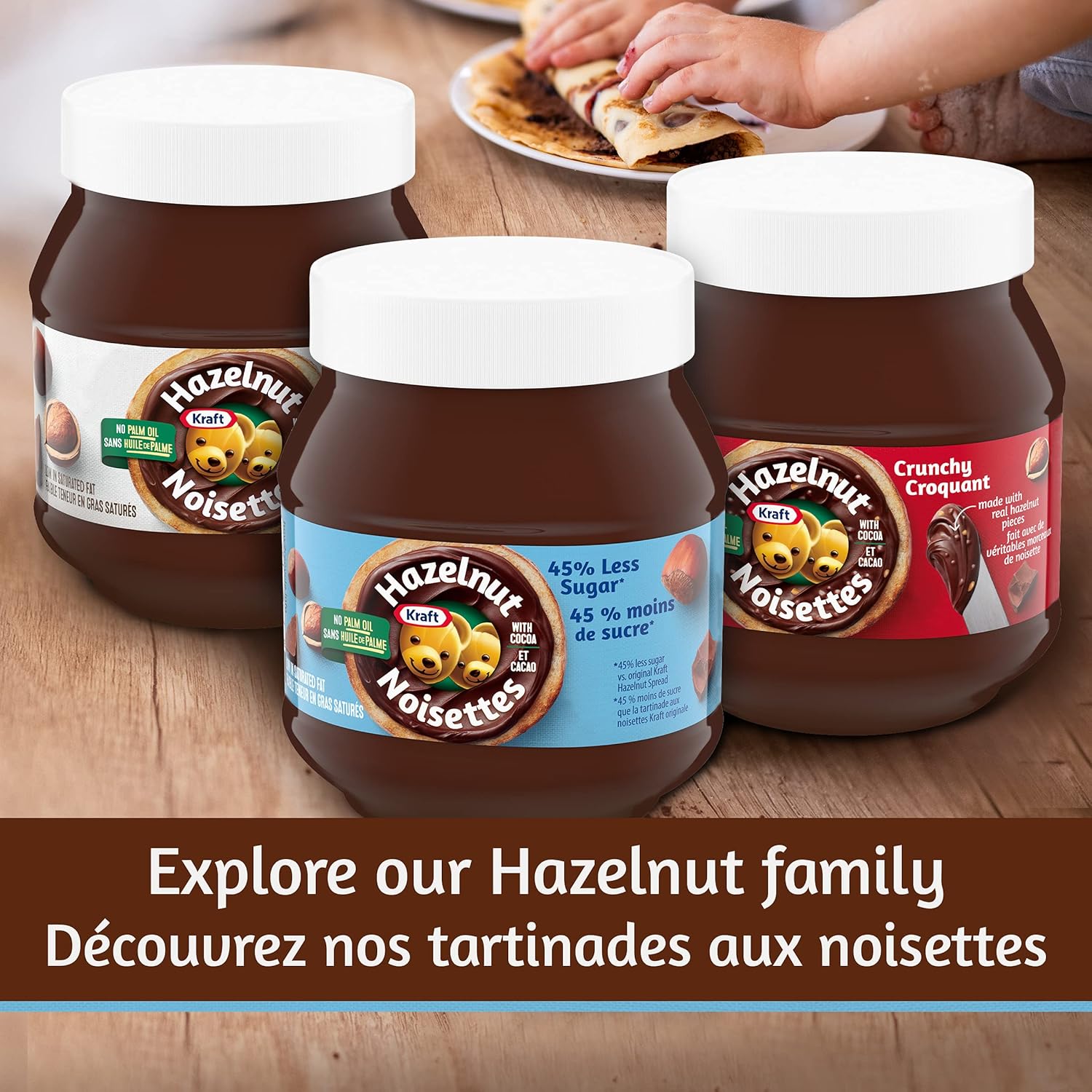 Three jars of Hazelnut Noisettes spread on a wooden surface with a person spreading it on bread.