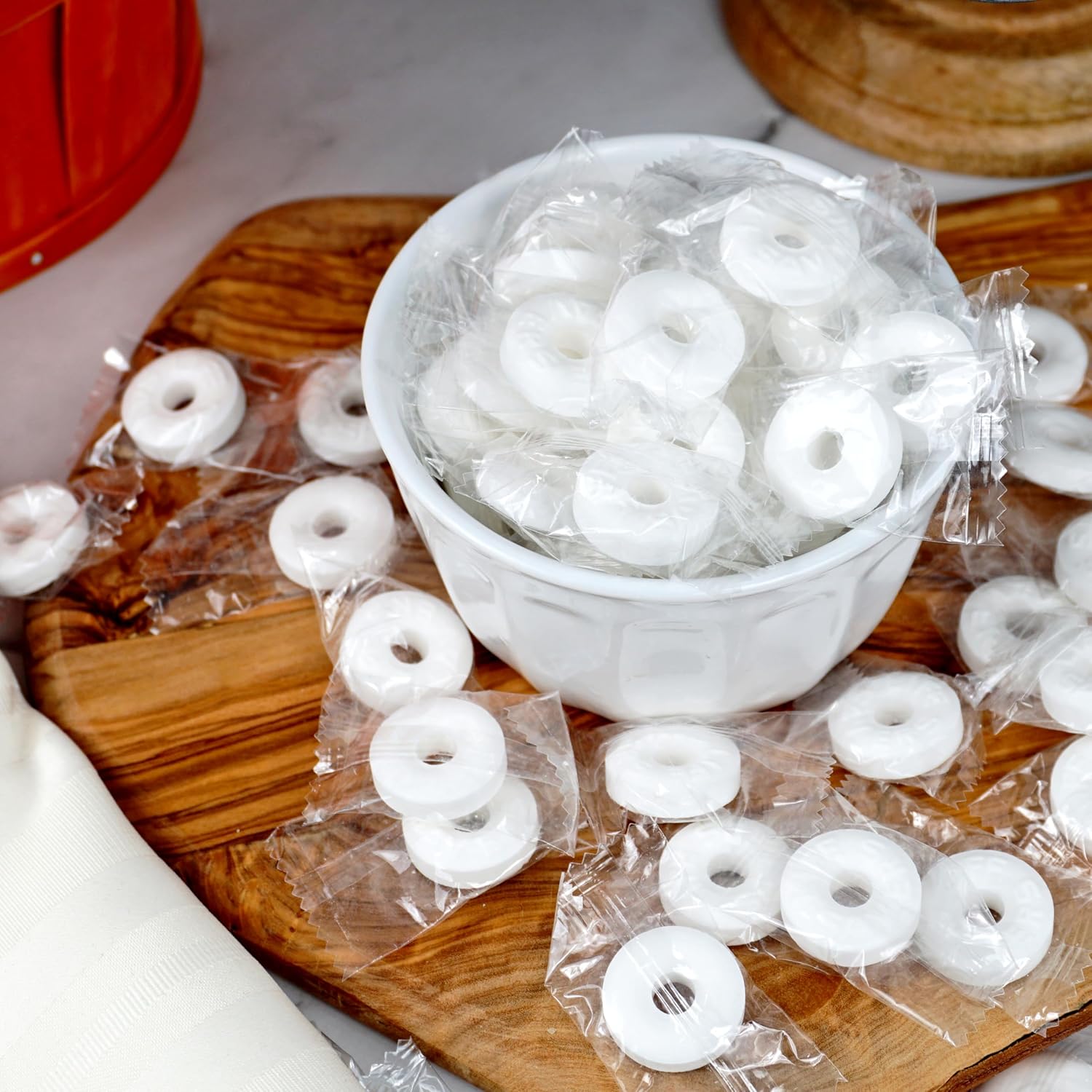 Life Savers Mints Pep-O-Mint candies in a bowl on a wooden cutting board with clear plastic wrap.
