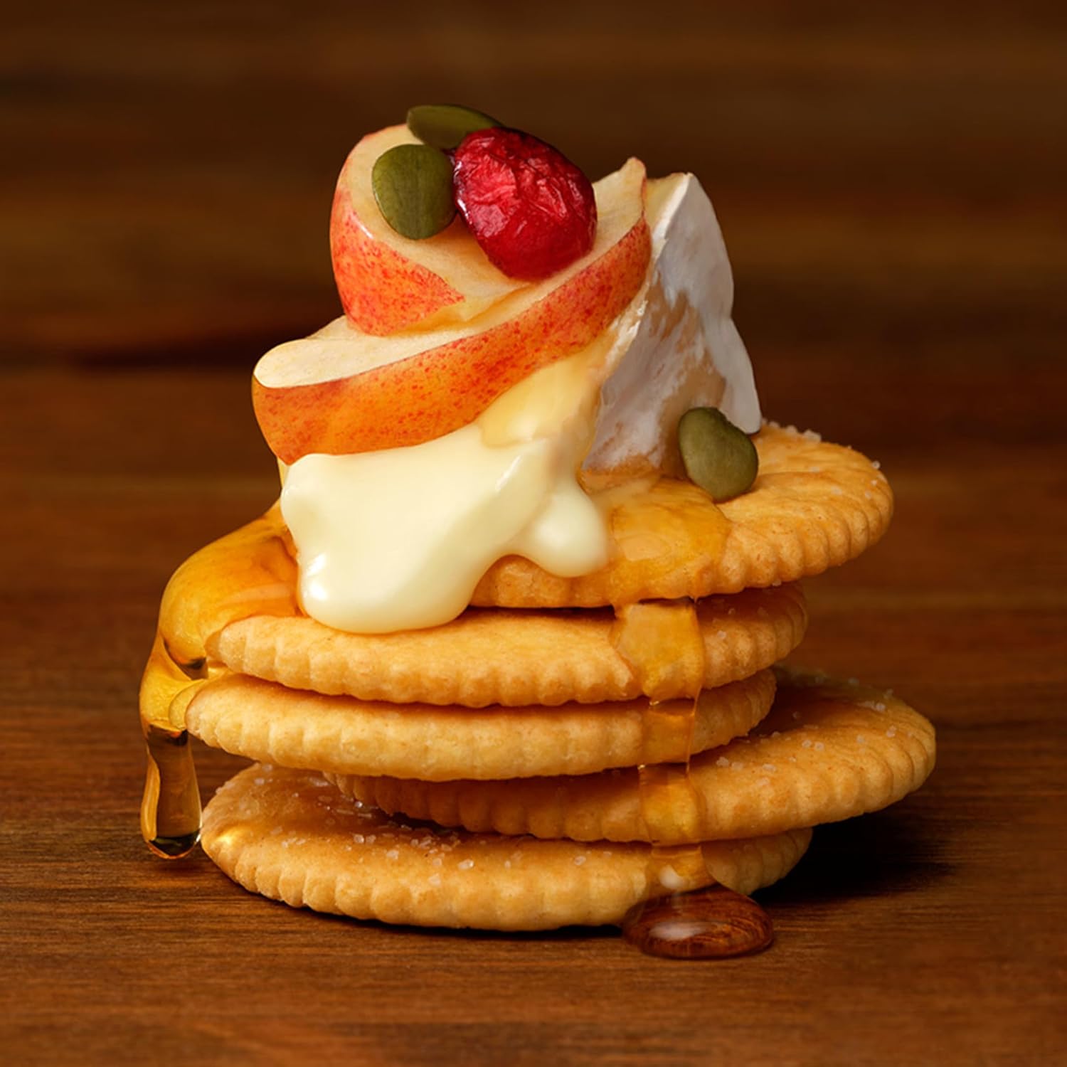 Stack of Ritz Low Sodium Crackers with fruit and cream on a wooden surface.