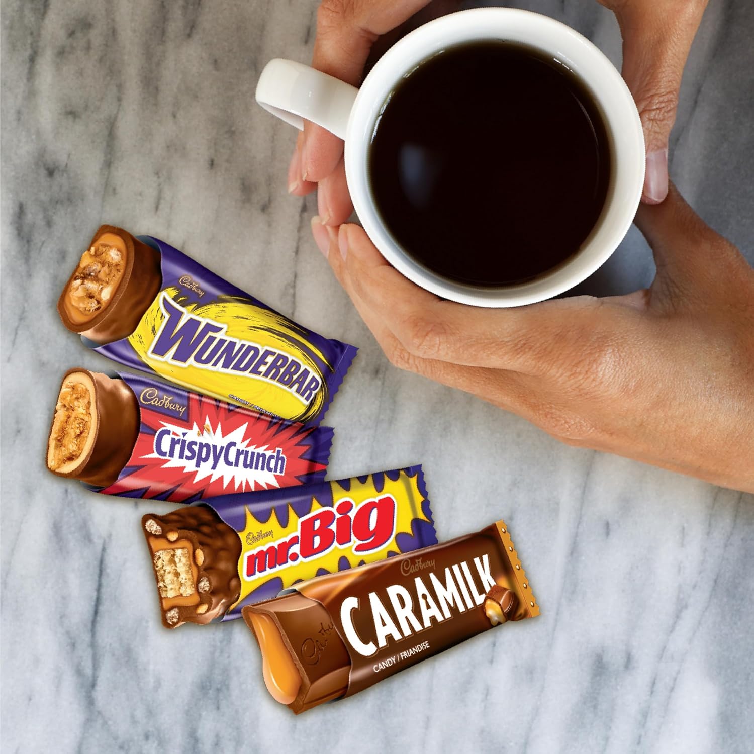 Cadbury snack-size Wunderbar, Crispy Crunch, mr.Big and Caramilk bars beside a cup of coffee on a marble surface