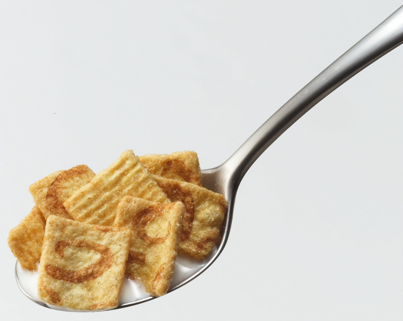 General Mills Cinnamon Toast Crunch Breakfast Cereal on a spoon with milk with a white background