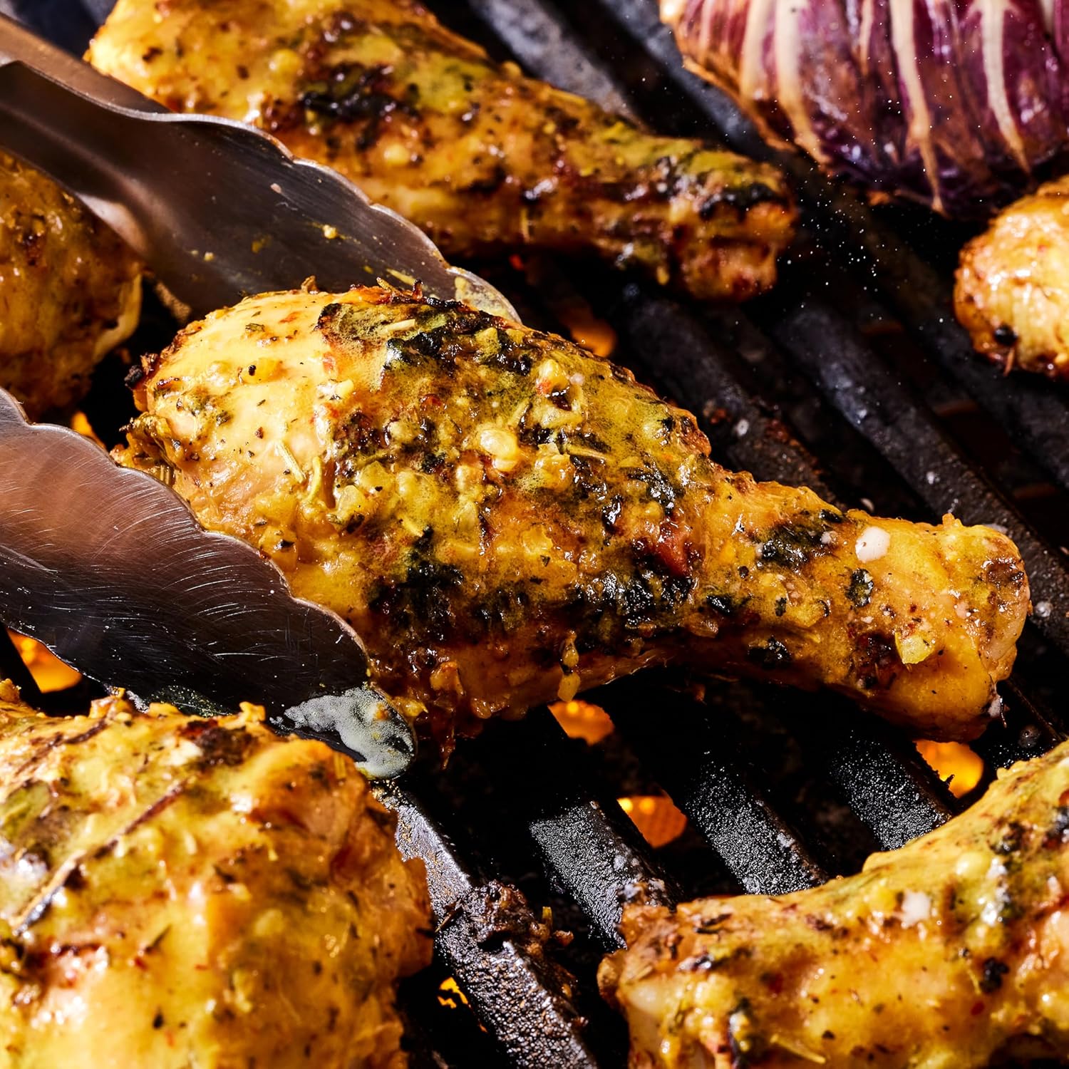 Grilled chicken drumsticks on a grill with tongs
