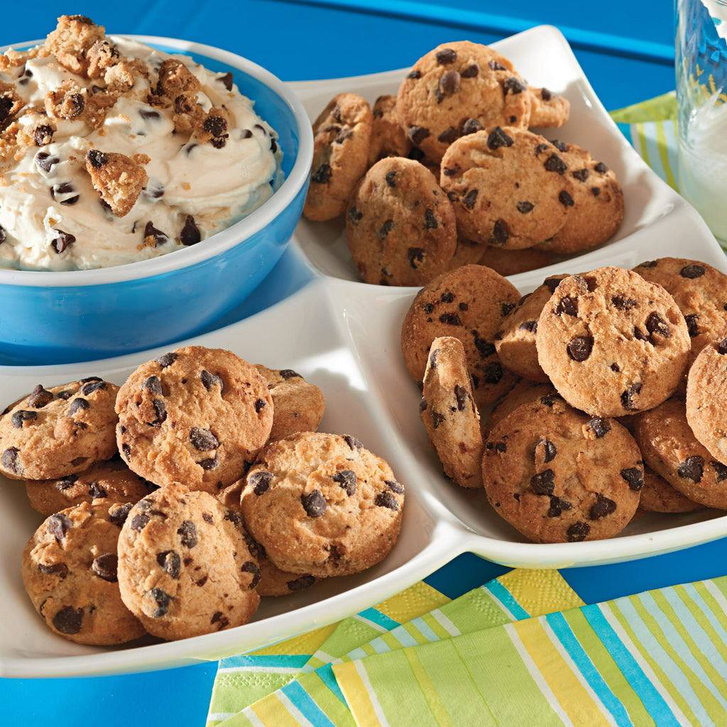 Dessert platter with cookie dip and chocolate chip cookies on a colorful tablecloth.