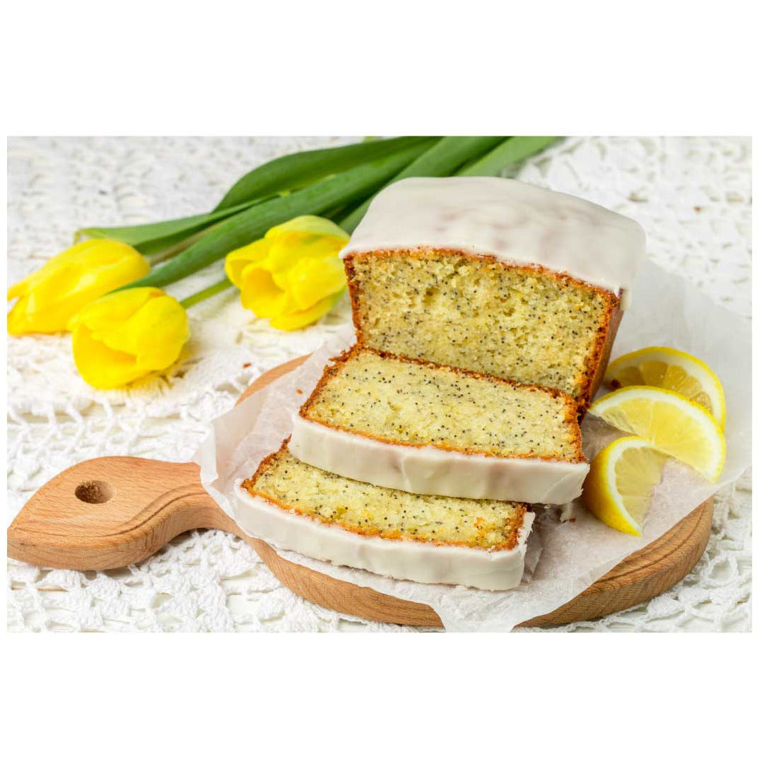 Sliced lemon cake with white icing on a wooden board with yellow tulips and lemons.