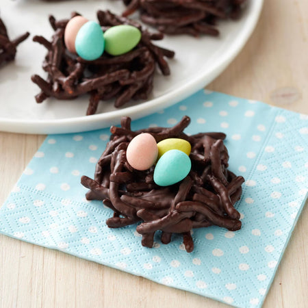 Chocolate nests with colorful eggs on a blue polka dot napkin