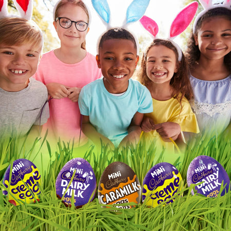 Children wearing bunny ears with Cadbury Easter eggs in the grass