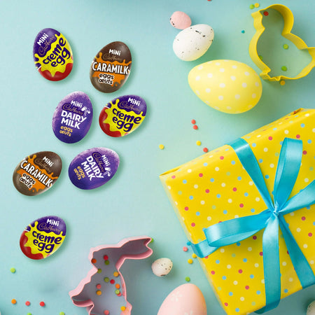 Mini Cadbury eggs with colorful packaging and Easter-themed items on a light blue background