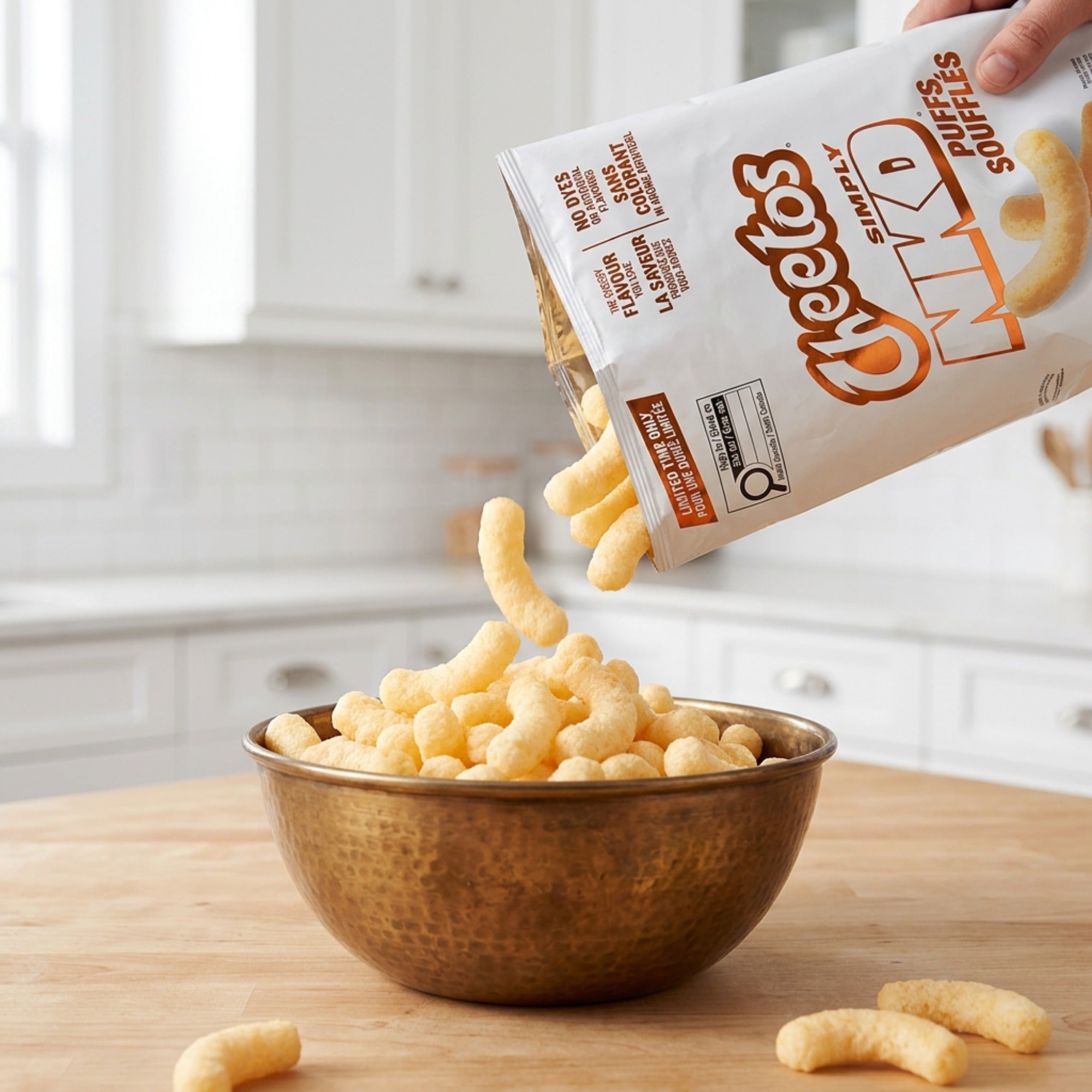 Cheetos Simply NKD pale golden cheese puffs being poured from the bag into a brown bowl.