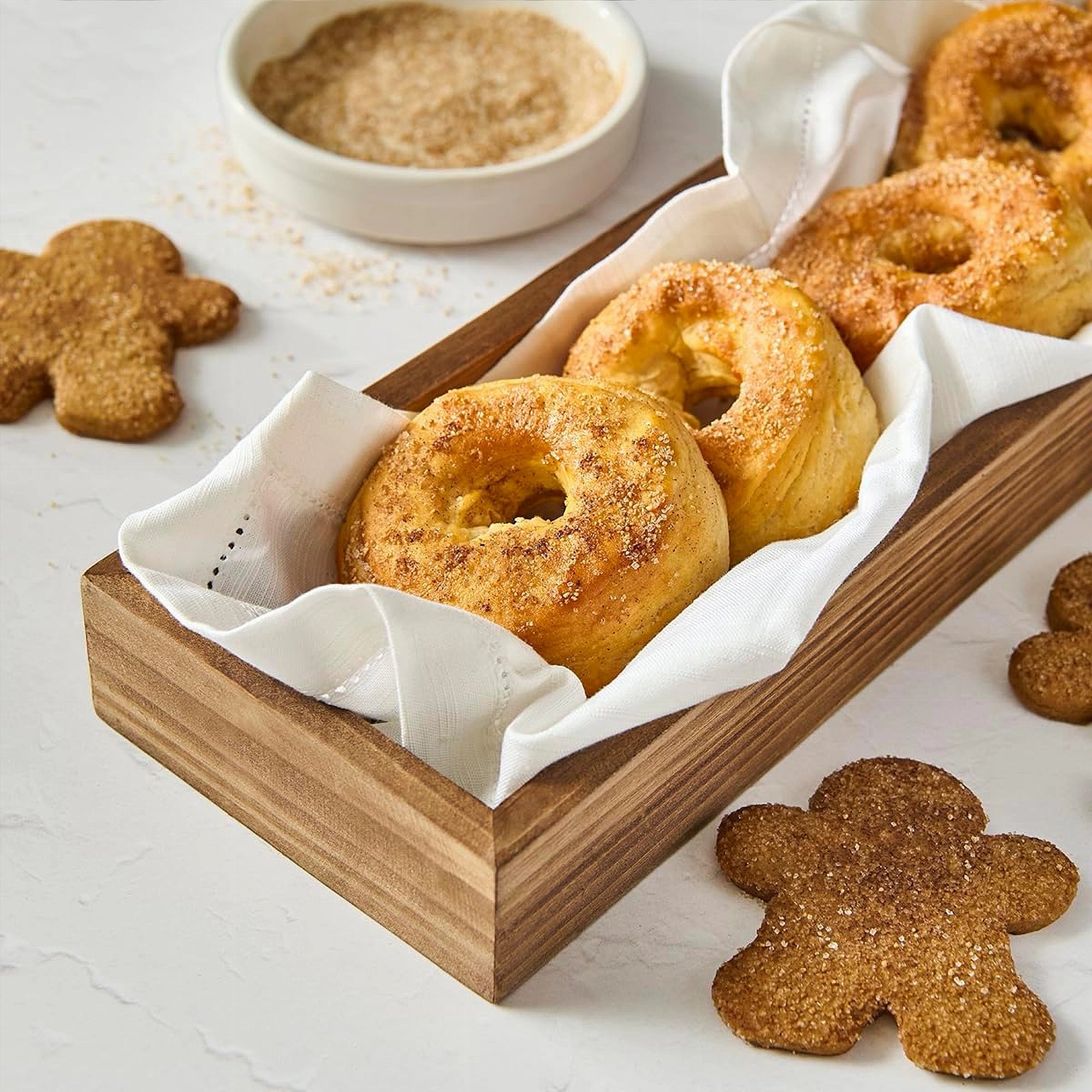 Wooden basket with baked goods and gingerbread men on a light surface