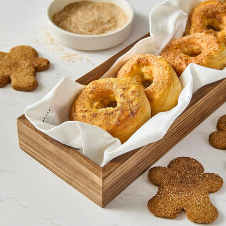 Wooden basket with baked goods and gingerbread men on a light surface