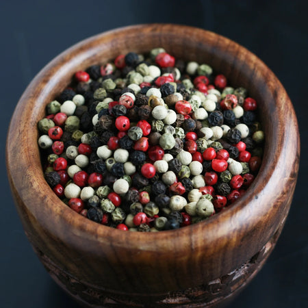 Close-up of Compliments 4 Peppercorn Blend showing whole black, white, green, and pink peppercorns
