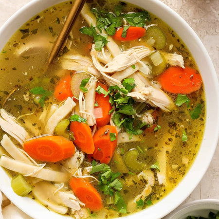 Homemade chicken soup made with Compliments Chicken Bouillon Concentrate — shredded chicken, carrots, celery in golden broth