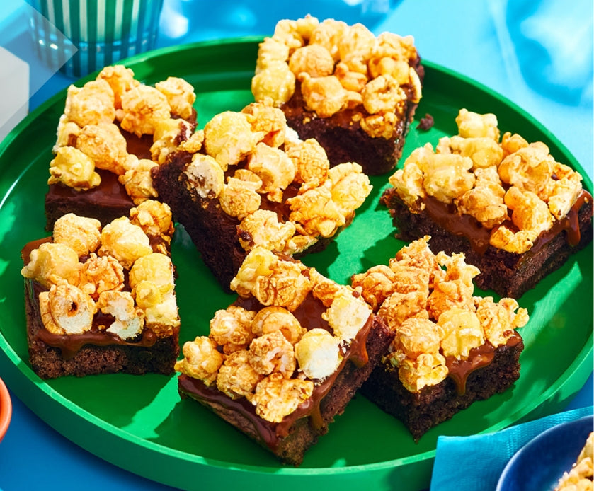 Brownies with popcorn on a green plate against a blue background
