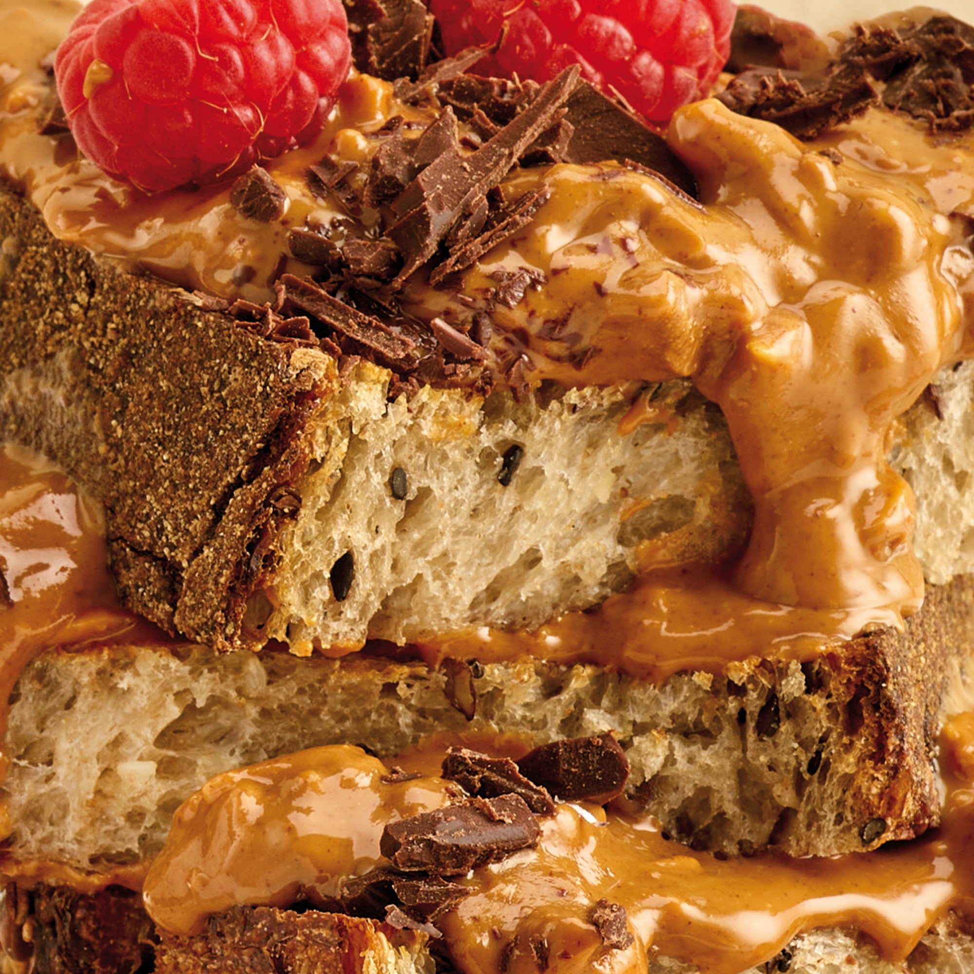 Close-up of a layered dessert with chocolate, peanut butter, and raspberries.