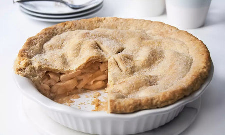 Apple pie with a slice taken out on a white plate