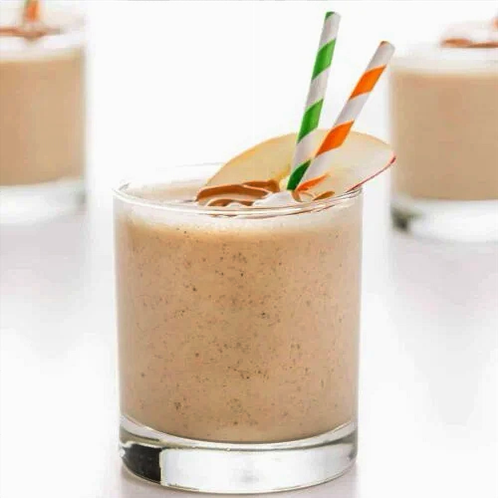 Glass of a peanut butter and apple smoothie with a straw on a white background