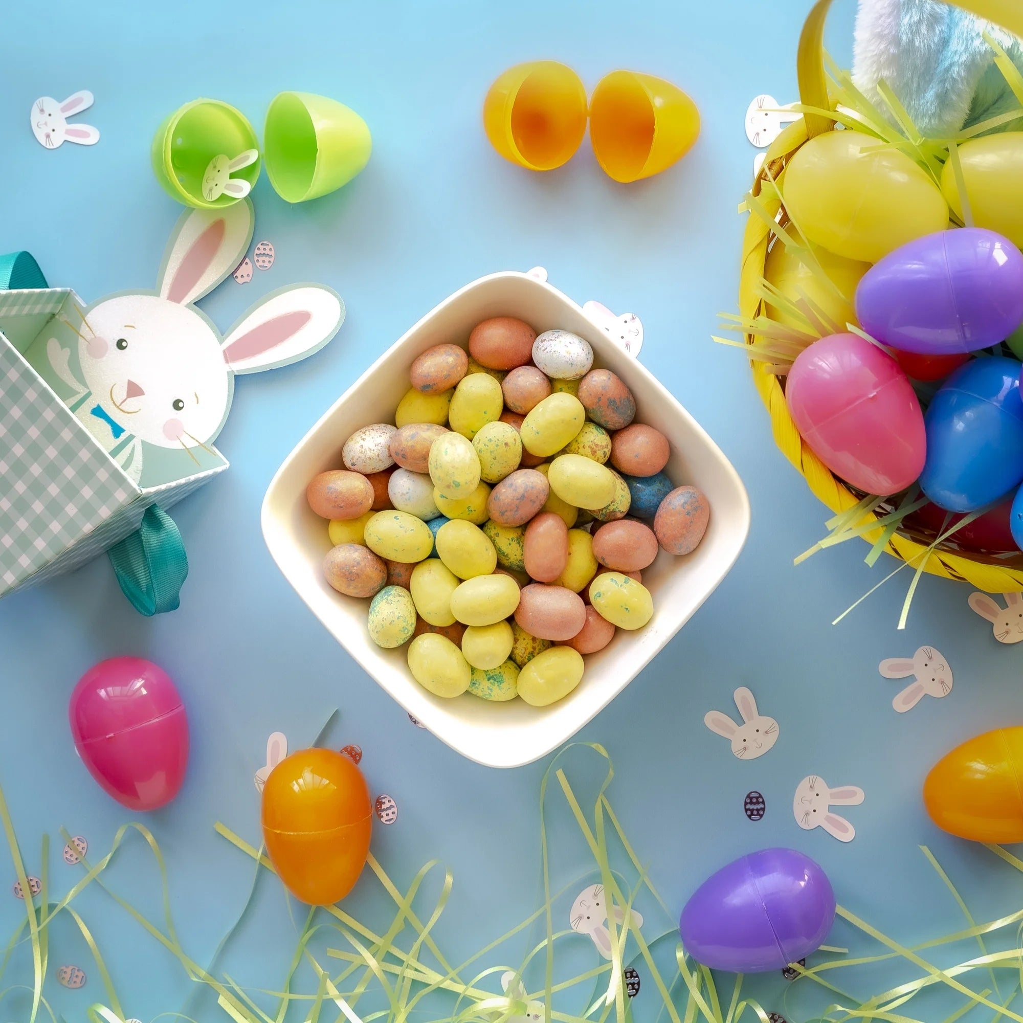 Colorful Easter-themed items including jelly beans, plastic eggs, and a bunny on a blue background.