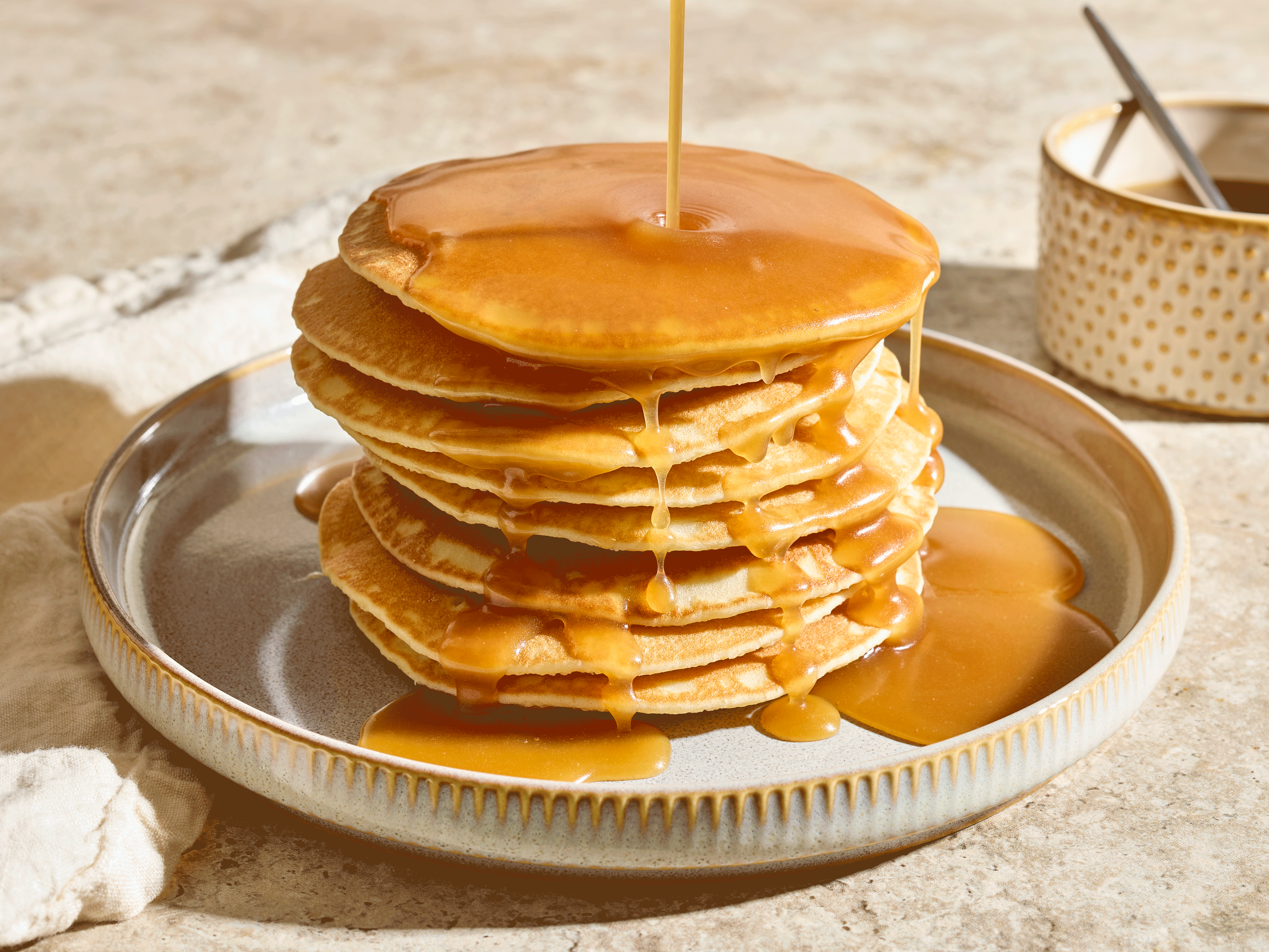 Maple butter spread poured over pancakes on a plate 
