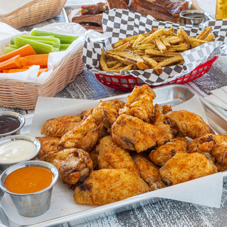 Crispy seasoned chicken wings and fries platter showing Kinder's Wood-Fired Garlic Seasoning used for BBQ and grilling