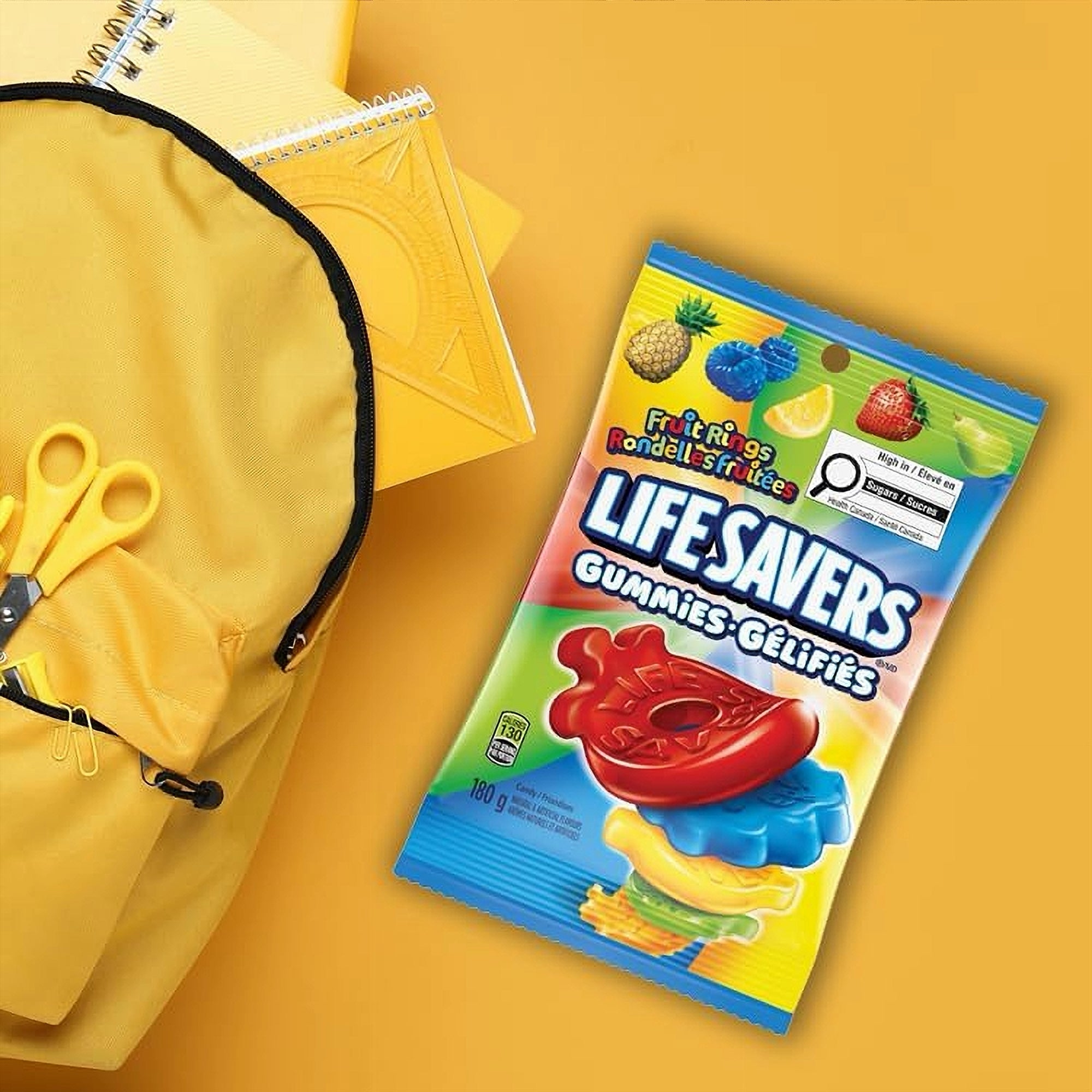 Lifesavers gummies package 180g on a yellow background with a yellow bag and scissors.