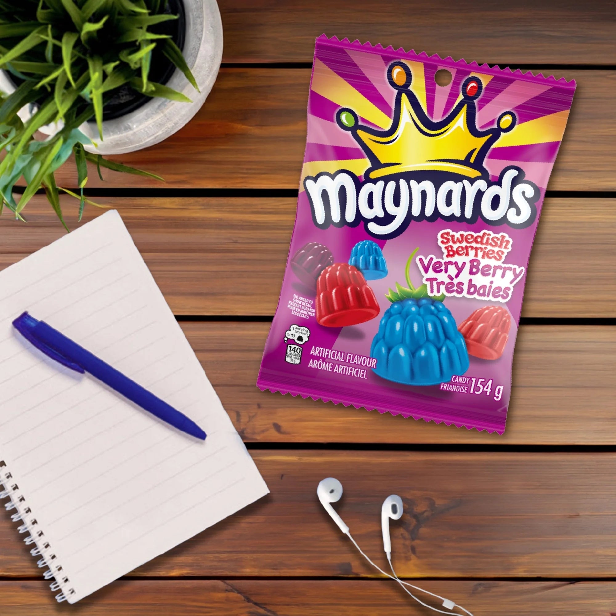 Maynards Swedish Berries Very Berry package on a wooden surface with a pen, notebook, and plant.
