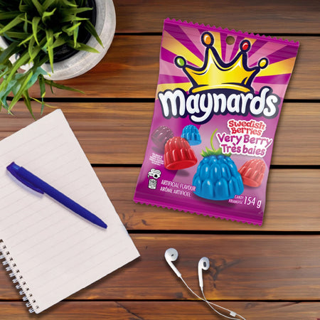 Maynards Swedish Berries Very Berry package on a wooden surface with a pen, notebook, and plant.