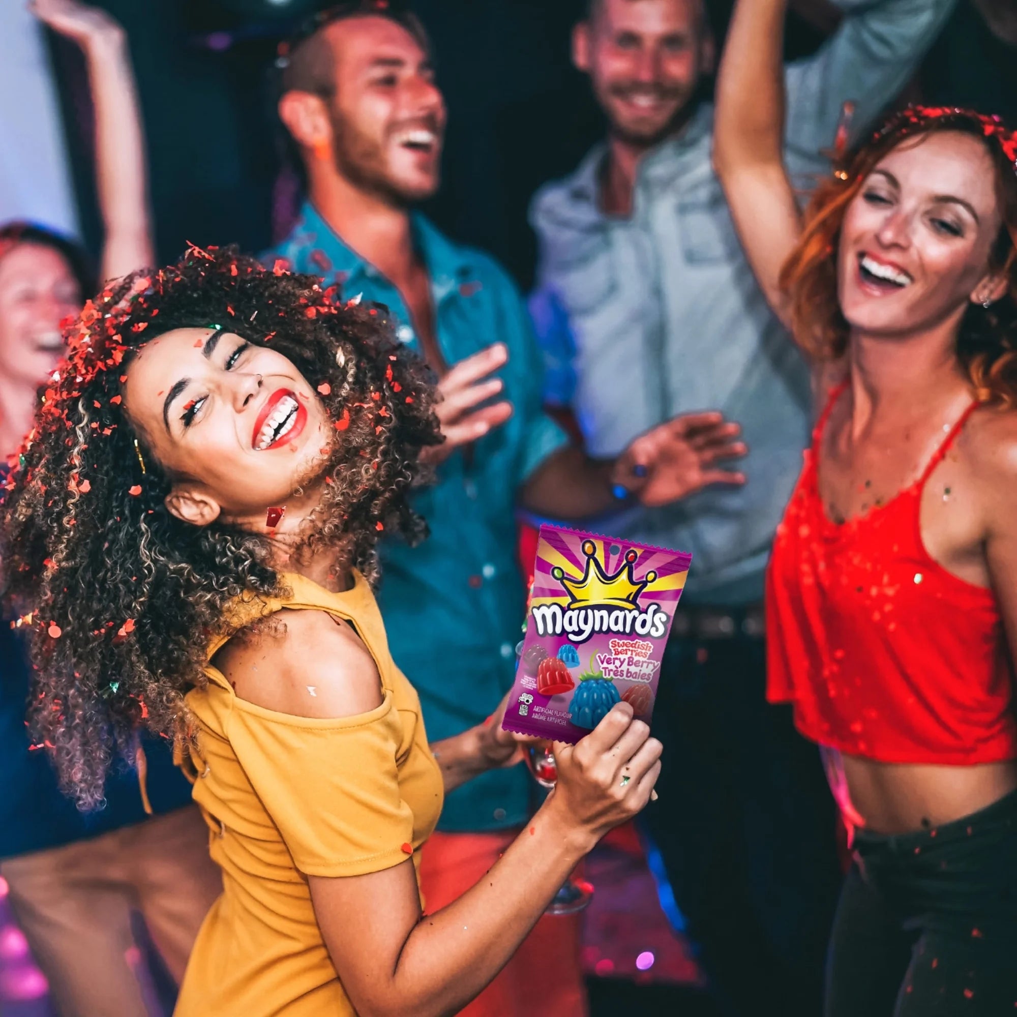 Woman holding a Maynards candy bag at a party with friends in the background
