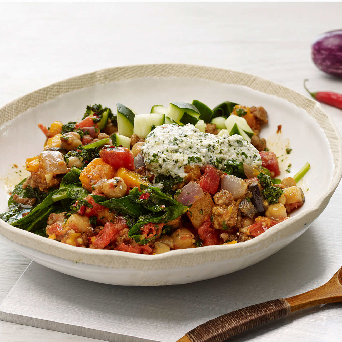 Bowl of colorful vegetable salad with a dollop of cream on a white surface