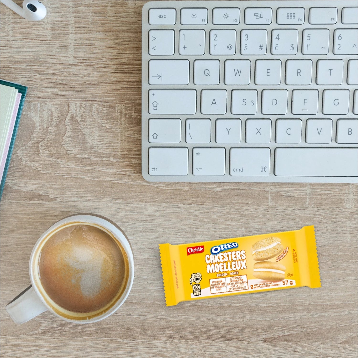 Cup of coffee, Oreo cookie bar package, and keyboard on a wooden desk