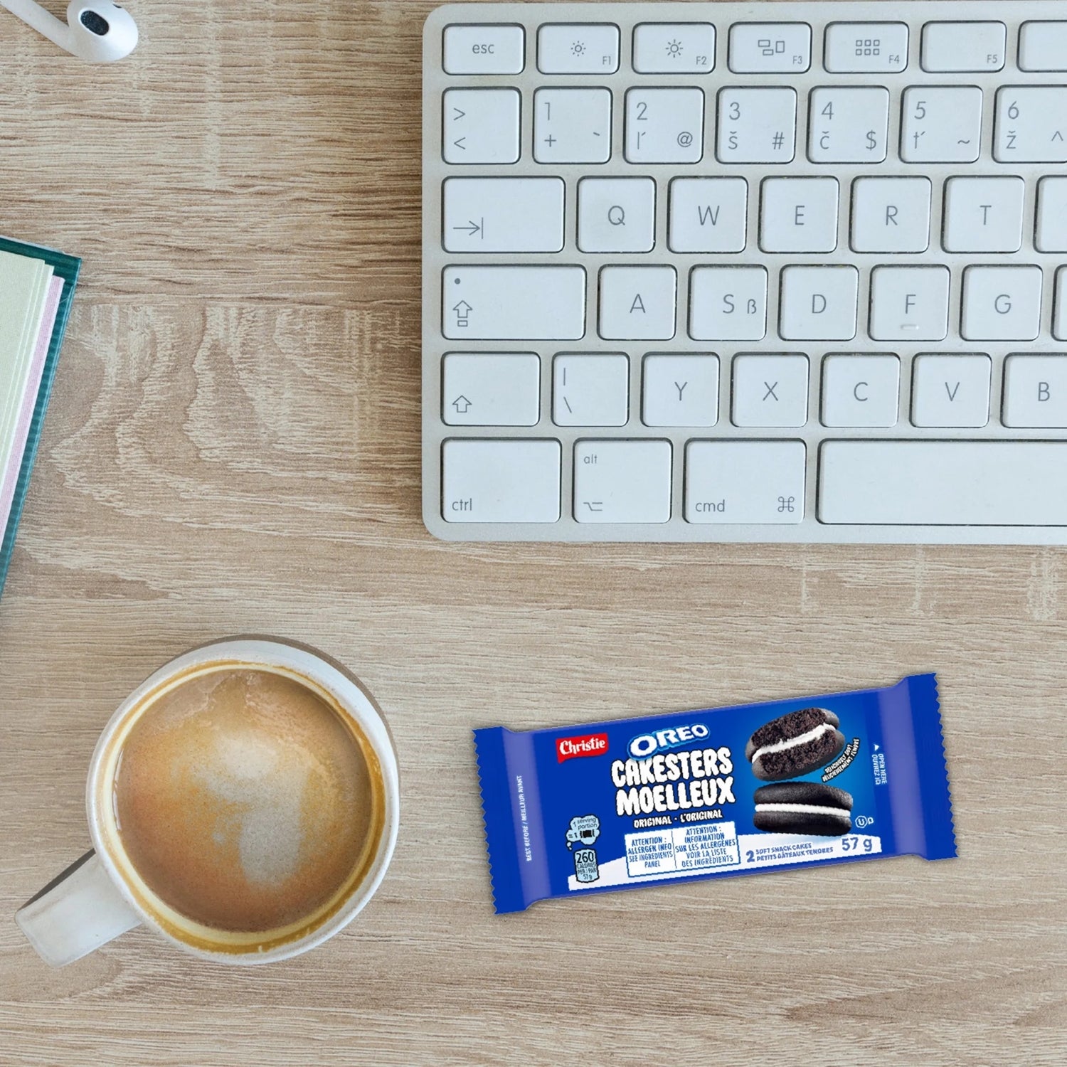 Cup of coffee, Oreo cookie bar package, and keyboard on a wooden desk