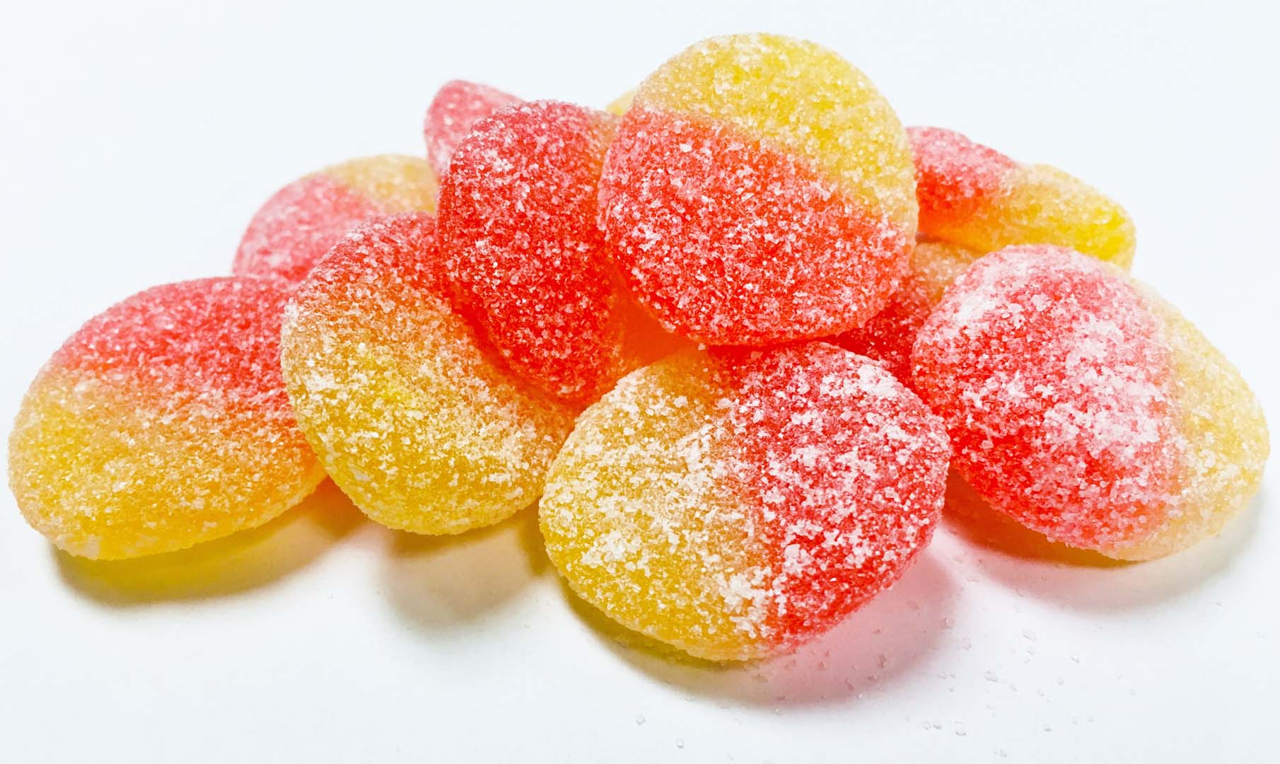 A pile of Allan Peach Slices Gummy Candy on a white background