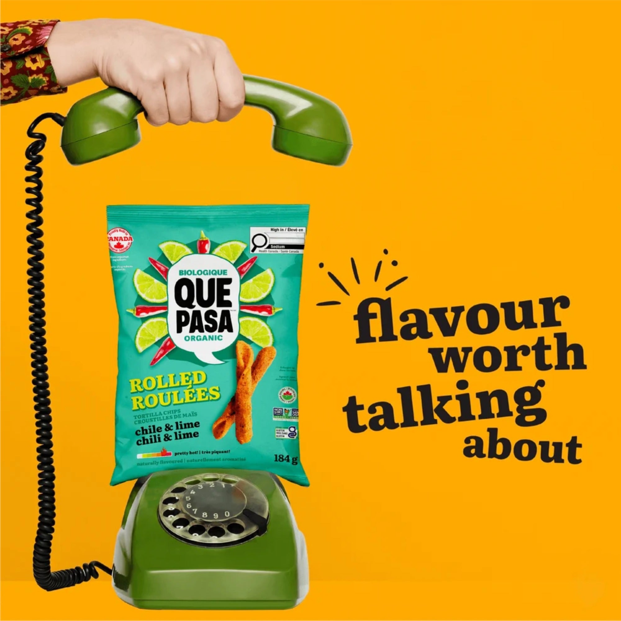 Que Pasa Chile & Lime Rolled Tortilla Chips on a green rotary phone beside “flavour worth talking about.