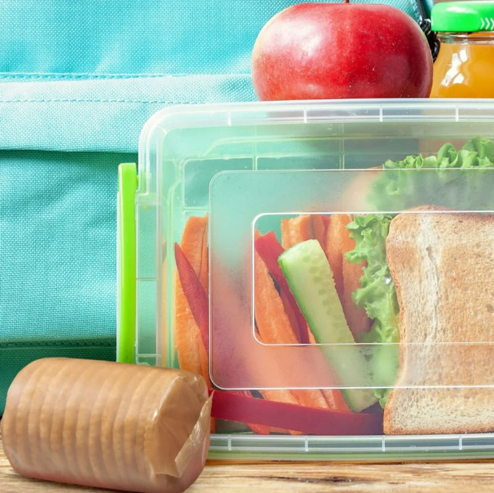 Lunch container with sandwich, apple, and juice box on a wooden surface