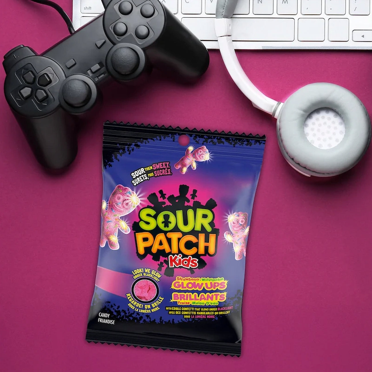 Sour Patch Kids candy package with gaming controller and headphones on a pink background