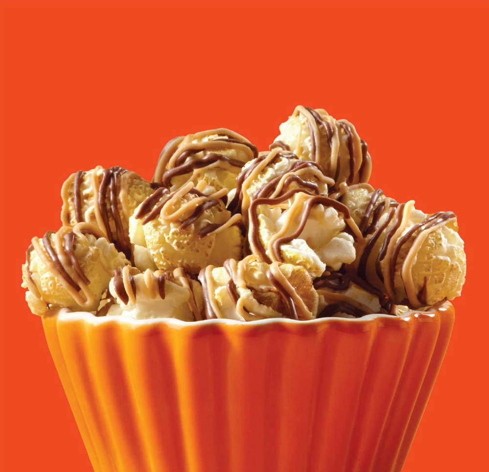 Bowl of popcorn balls drizzled with chocolate on an orange background